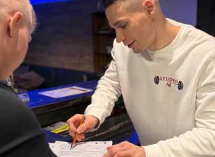 Studio M Beratung zu Tarifen mit Kunden und Trainer am Tresen