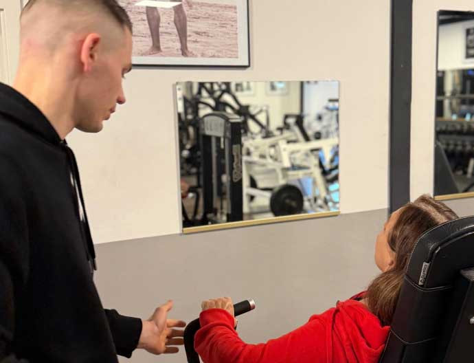 Studio M Personaltraining Trainer mit Kundin am Gerät